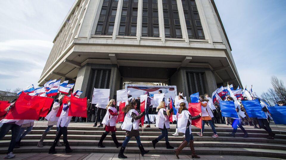 Участники торжественного митинга по случаю празднования годовщины "Крымской весны" на площади у Государственного Совета РК в городе Симферополе
