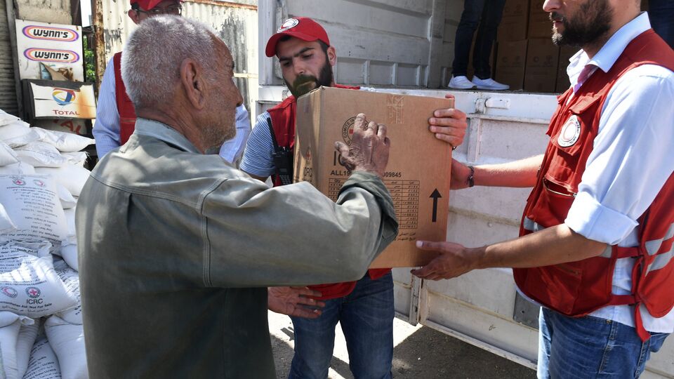 Представители Сирийского арабского красного полумесяца раздают гуманитарную помощь жителям квартала Кабун в пригороде Дамаска